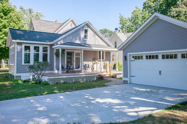 Une maison à deux étages avec un porche couvert, un garage et une pelouse bien entretenue.