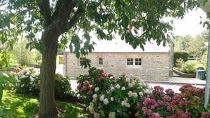 A stone building with a garden in front. - Charming cottage with a veranda facing south overlooking an orchard. (Colleville-sur-Mer)