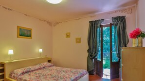 Une chambre à coucher avec un lit, deux lampes de chevet, un tableau, une fenêtre avec des rideaux et une armoire en bois.