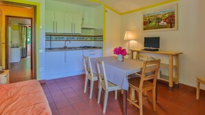 A compact kitchen with white cabinets, a dining area with a table and chairs, and a painting on the wall. - Residence a Pistoia ID 3781 (Pistoia)