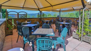An outdoor patio with tables and chairs under a large canopy, overlooking a mountainous landscape. - Residence a Pistoia ID 3781 (Pistoia)