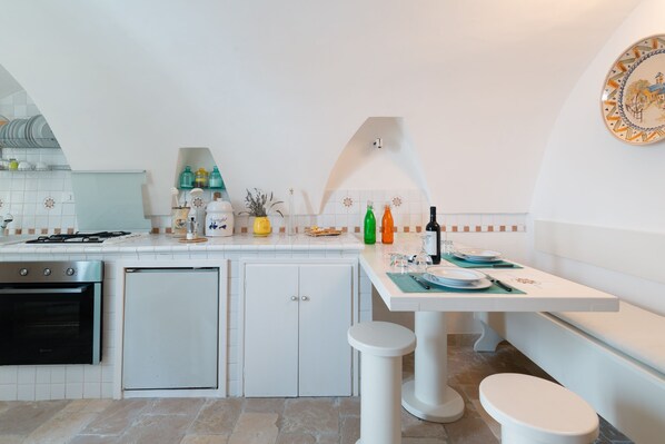 A modern kitchen with white cabinets, a built-in oven, and a dining area with a table set for two.