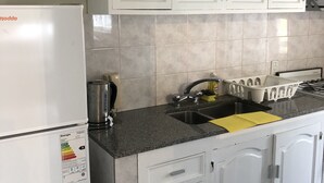 A kitchen with white cabinets, a stainless steel sink, and a white refrigerator. - Amplio & Luminoso Depto Centro de Salta (Salta)