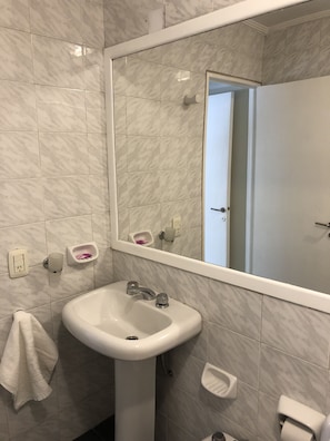 Een badkamer met een witte wastafel, een spiegel, een handdoek en een zeepdispenser.