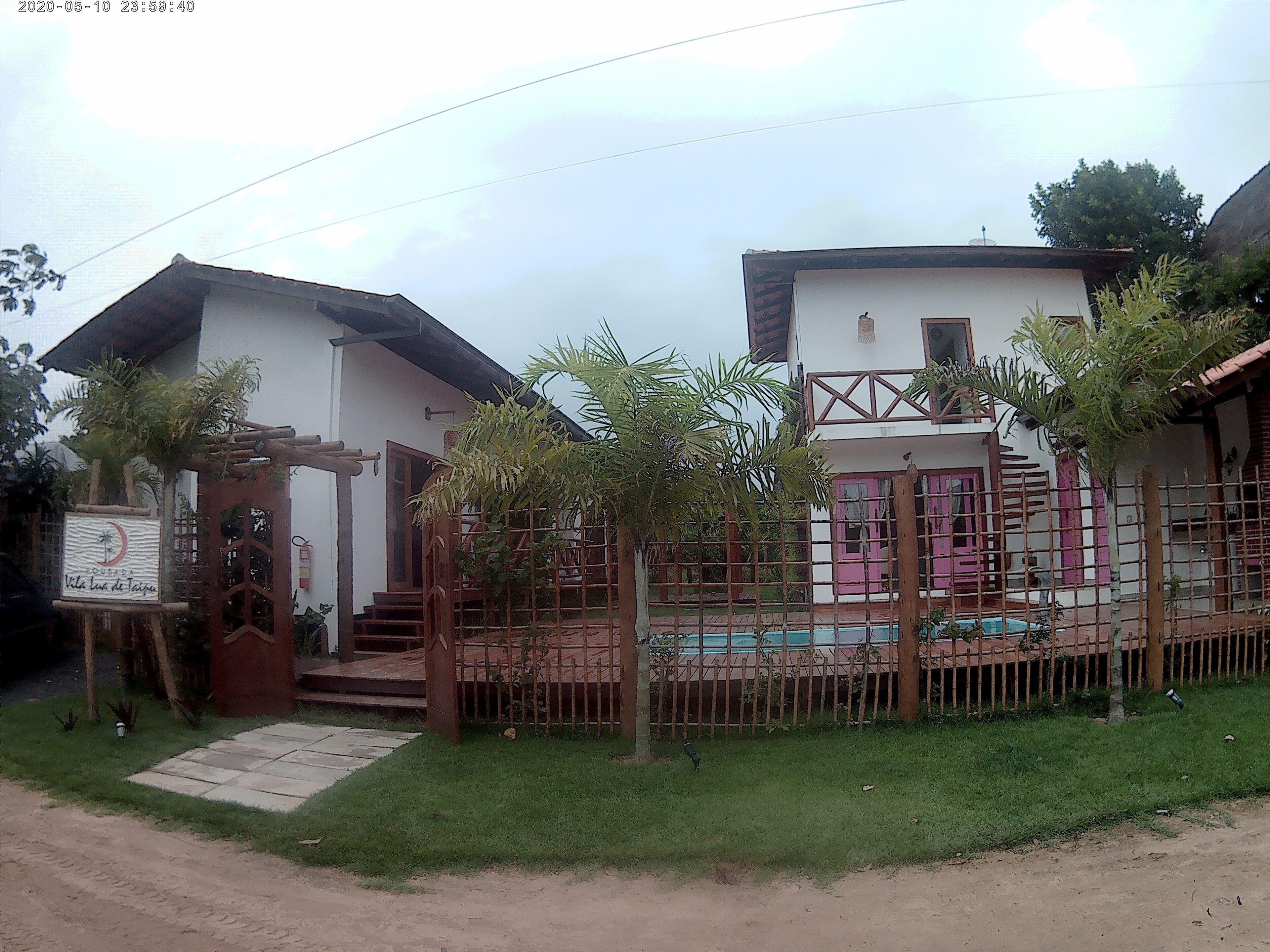 A two-story house with a fenced yard, a small pool, and a signboard.