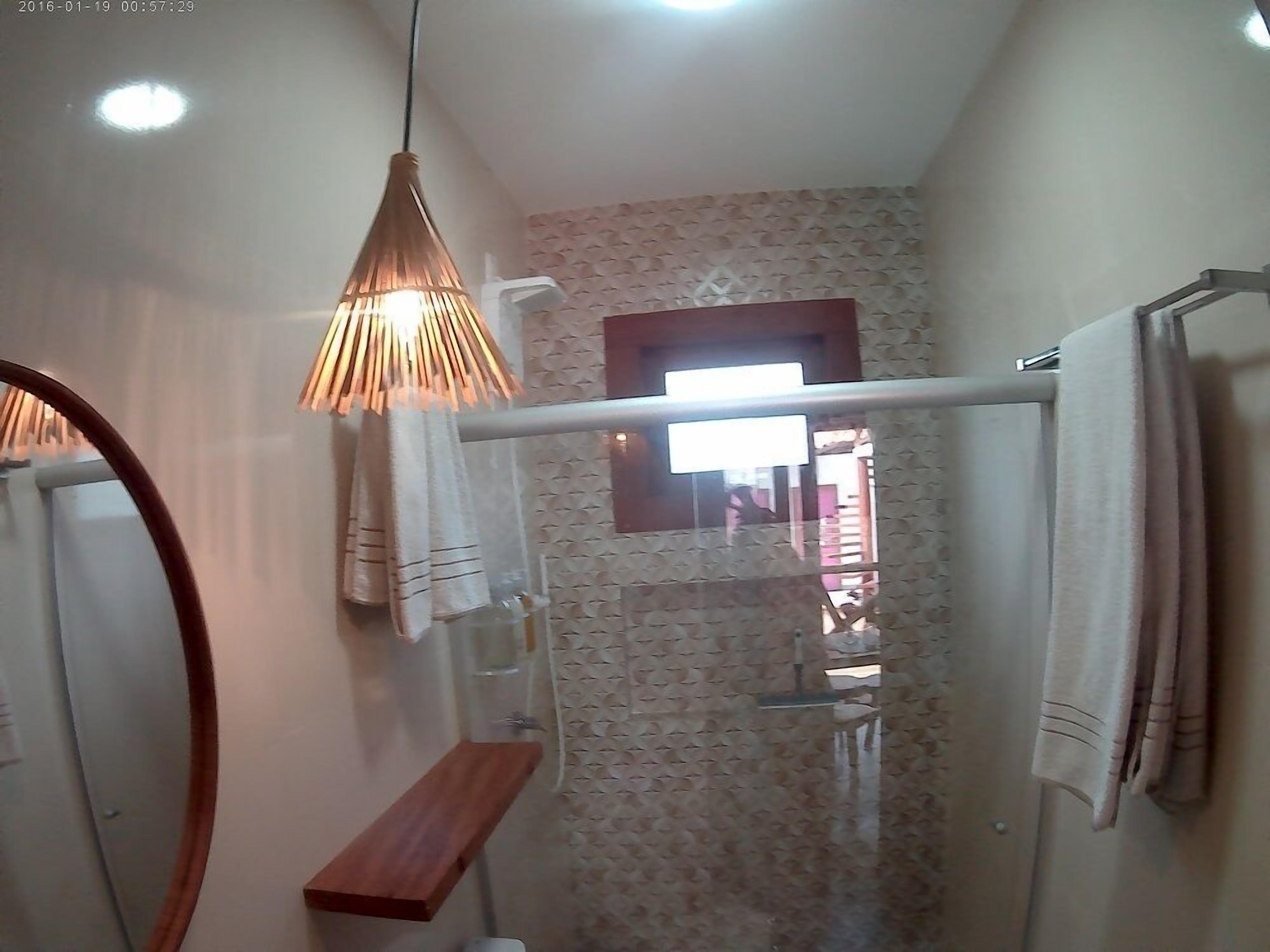 A bathroom with a wooden shelf, a towel rack, and a shower area.