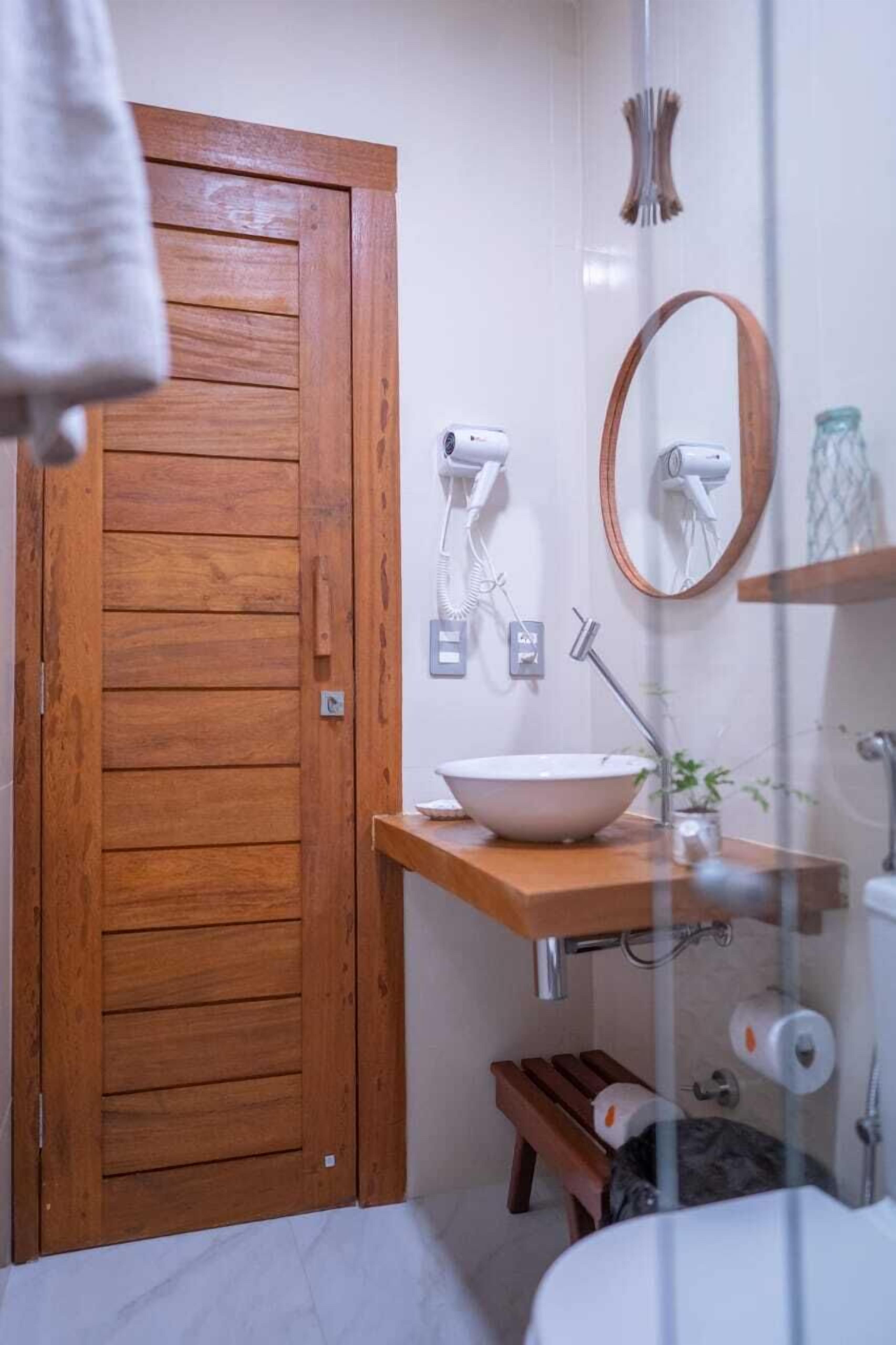 A bathroom with a wooden door, a sink with a bowl, a mirror, and a towel hanging on the door.