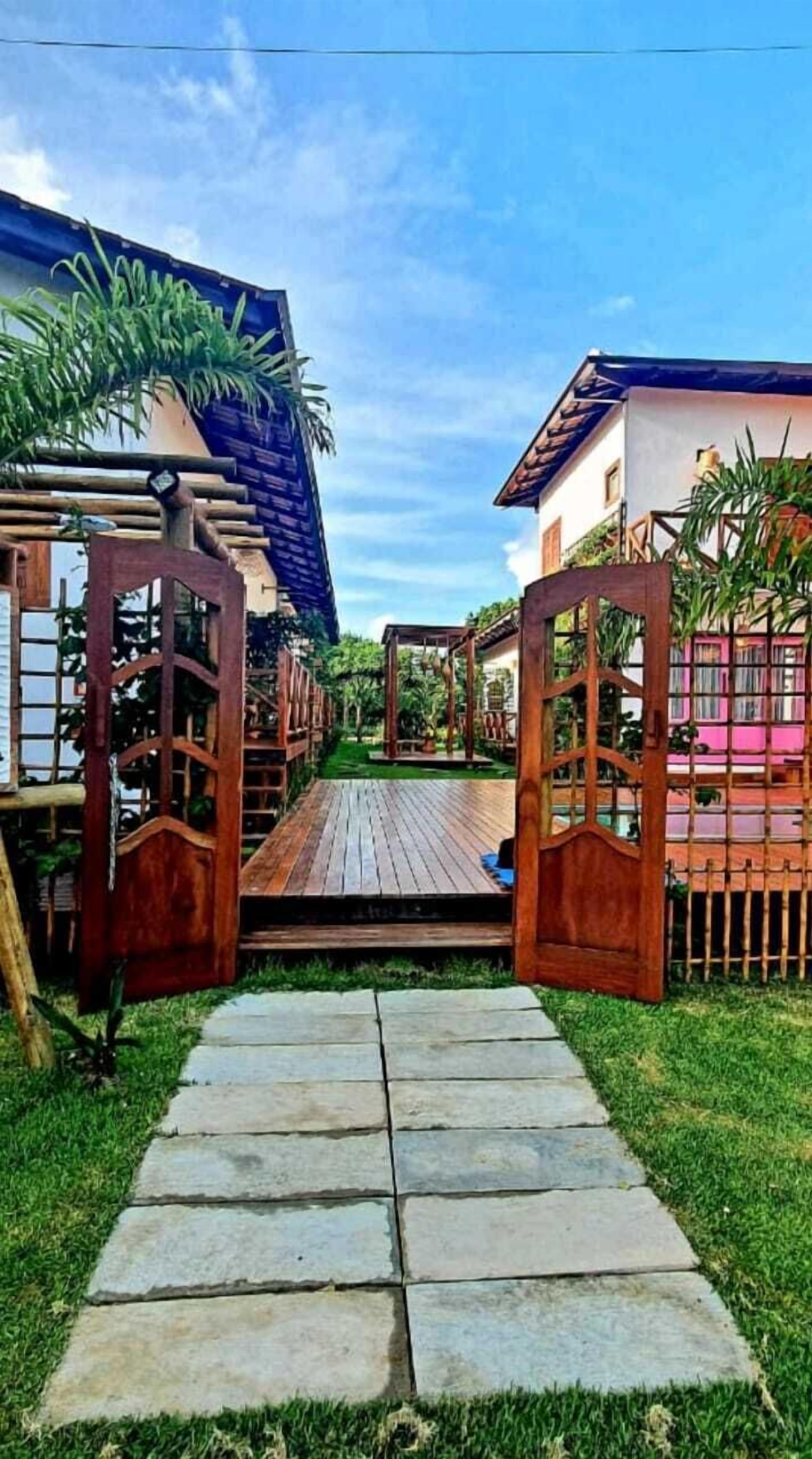 A wooden pathway leading to a covered area with a pergola and a small deck.