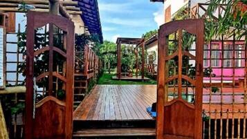 A wooden pathway leading to a covered area with a pergola and a small deck.