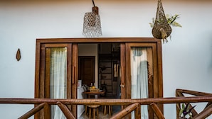 Ein hölzerner Balkon mit Blick auf einen Innenraum, einer hängenden Leuchte und einer hängenden Pflanze.