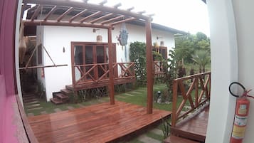 Una terraza de madera con escalones que conducen a un edificio blanco con una ventana y una puerta.