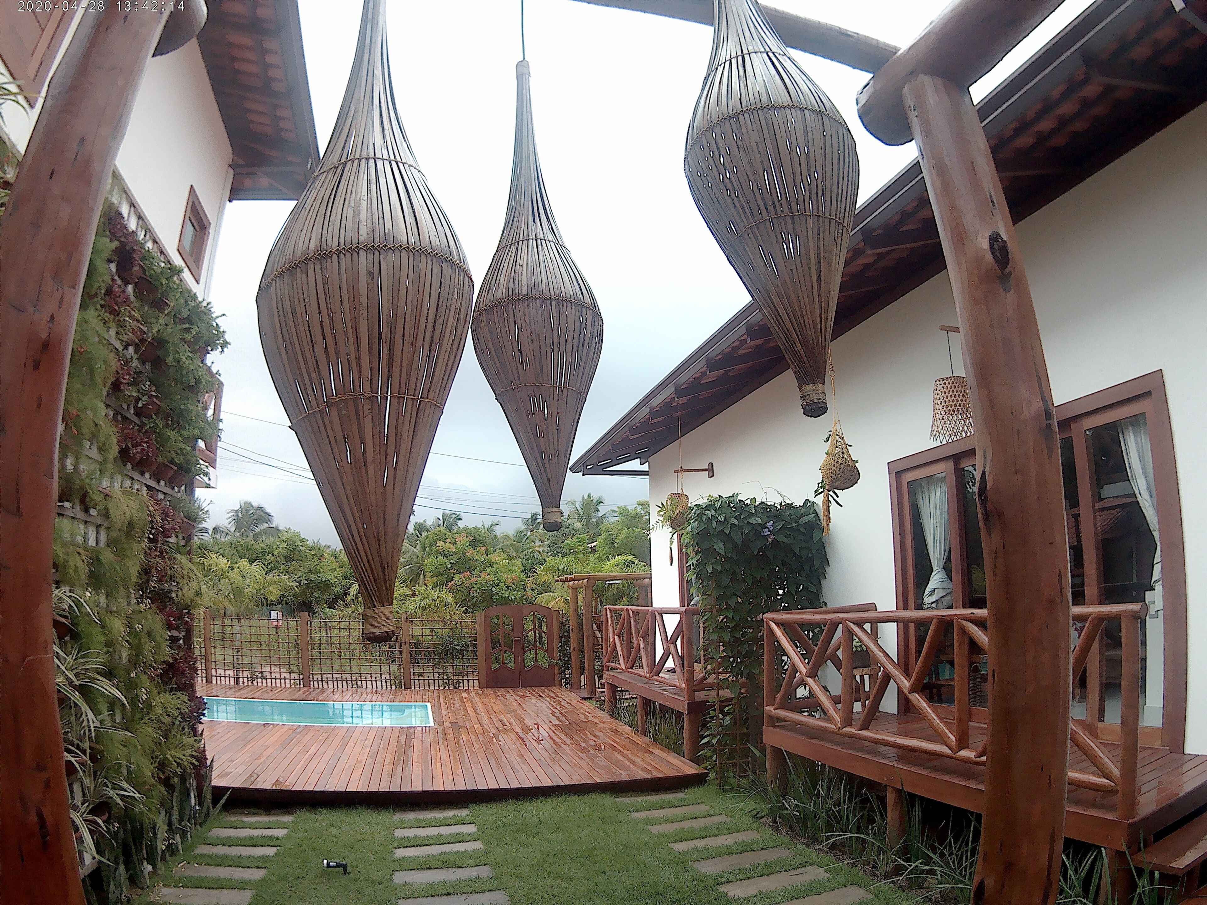 Um deck de madeira com piscina, cercado por um muro de madeira e plantas.