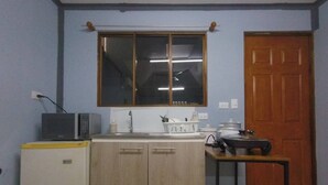 Une cuisine de taille réduite comprenant un évier, des placards, un four à micro-ondes, une petite table et une fenêtre.
