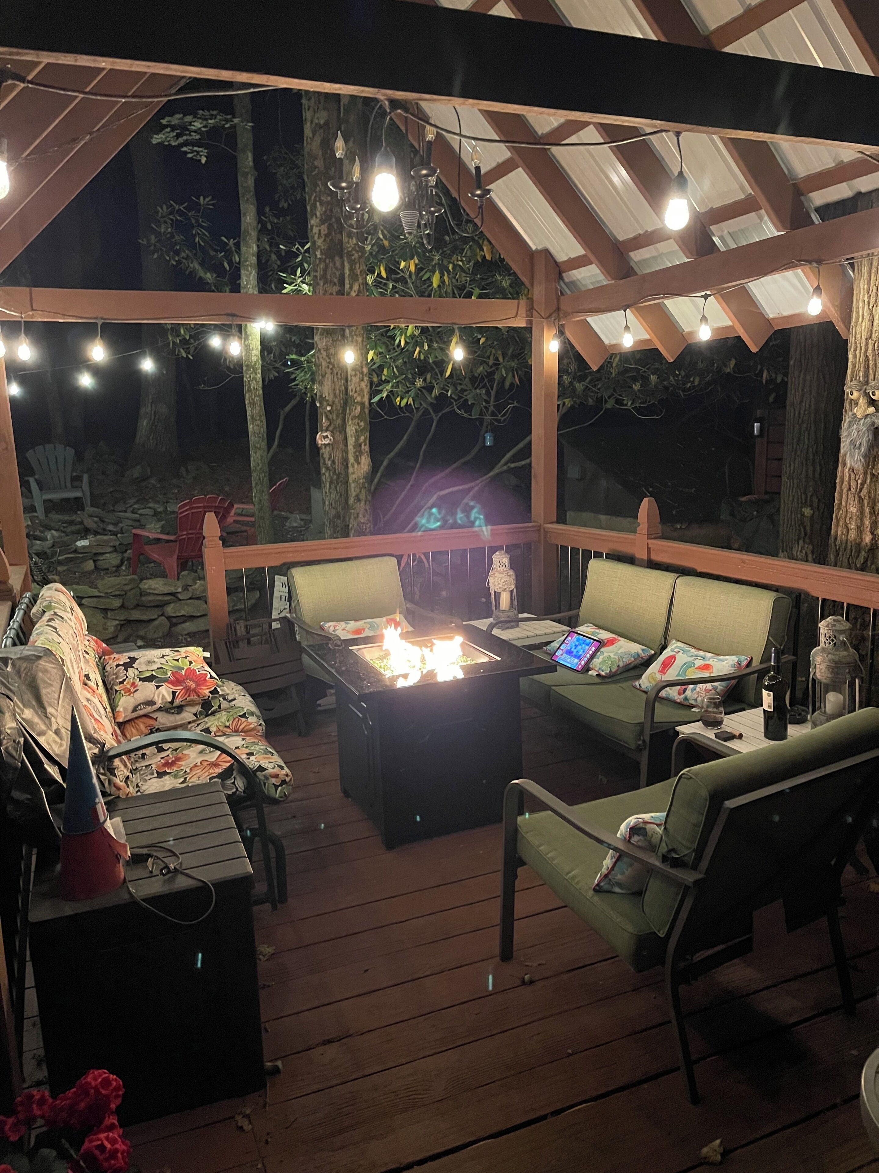 An outdoor patio with a fire feature, seating, and string lights.
