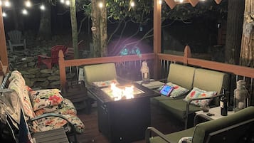 An outdoor patio with a fire feature, seating, and string lights.