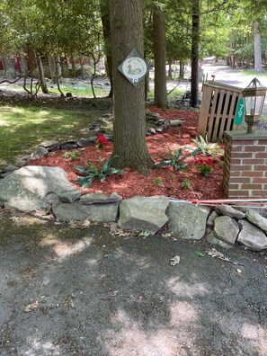 A landscaped garden area with a welcome sign, a brick wall, and a wooden fence.
