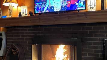 A fireplace with a TV mounted above it, displaying a basketball game.