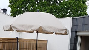 A wooden deck with a grill, outdoor furniture, and a yellow cat statue. - Cosy cottage with terrace and private parking (Guidel)
