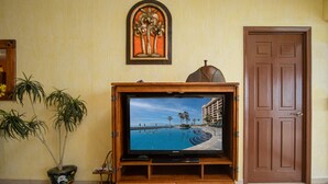 Een houten entertainmentcentrum met een flatscreen-tv waarop een scène van een zwembad te zien is, een deur en een decoratief object aan de muur.