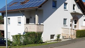 A two-story house with a solar panel roof, a brick chimney, and a small garden area. - Apartment Kempf Mandelbachtal Saarland (Mandelbachtal)