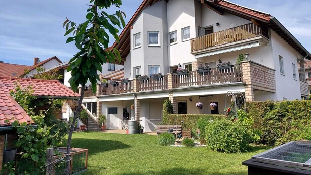 A two-story residential building with a balcony, a covered porch, and a well-maintained garden. - Apartment Kempf Mandelbachtal Saarland (Mandelbachtal)
