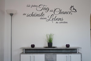 A wall with a motivational quote in German, a potted plant, and two decorative bowls on a countertop.