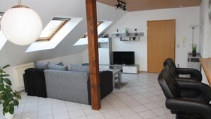 A modern living room with a sofa, TV, and seating area. - Apartment Kempf Mandelbachtal Saarland (Mandelbachtal)