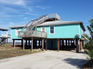 A two-story house with a wooden staircase leading to a balcony, elevated on stilts.