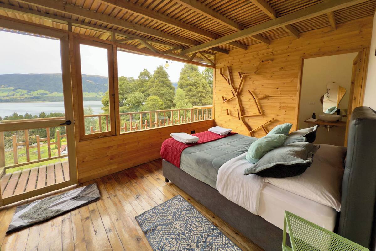 Eine Holzhütte mit Bett, Fenster und Seeblick.