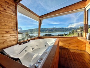 Une cabane en bois avec un jacuzzi et une vue sur un lac et des montagnes.