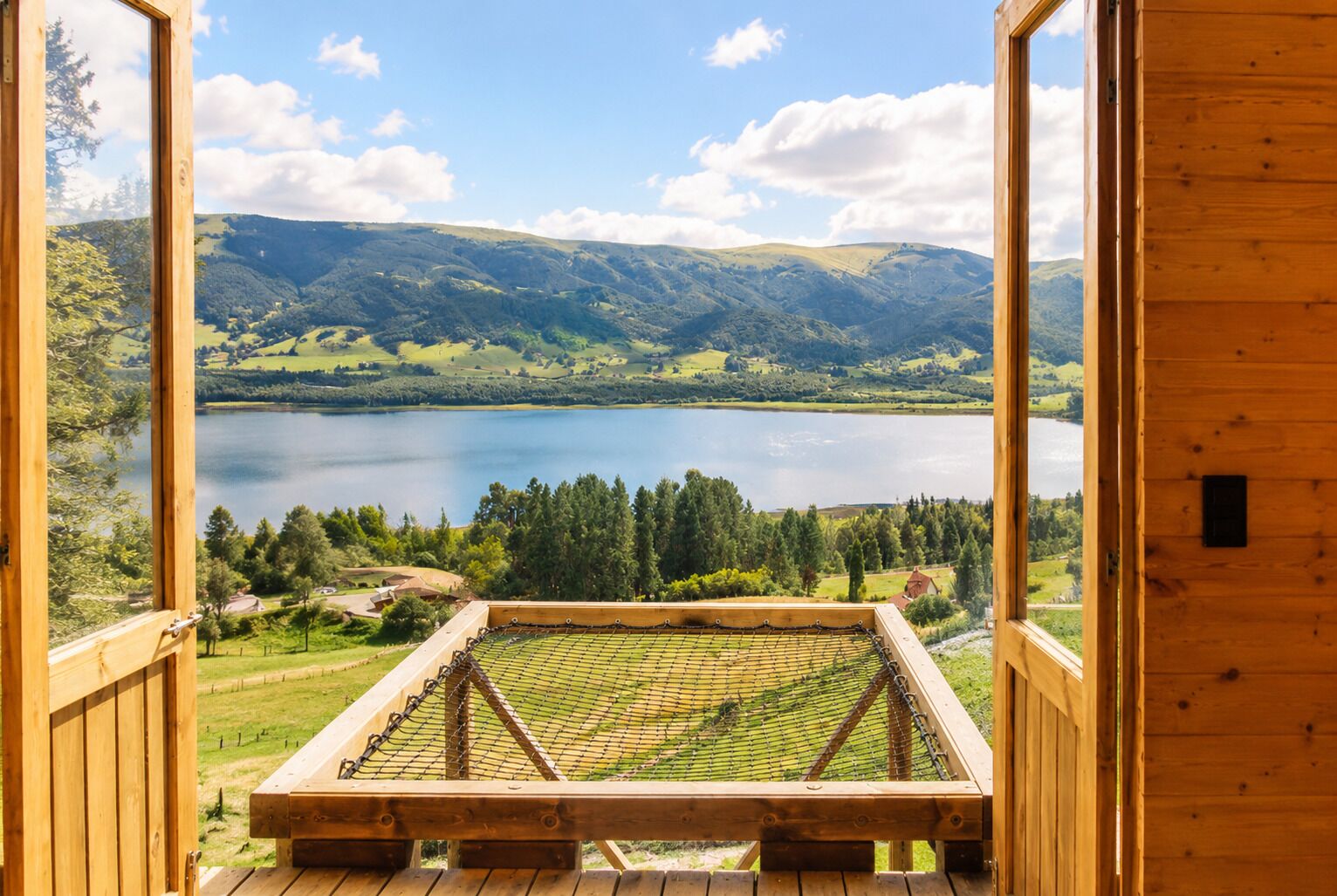 A wooden deck with a view of a lake and surrounding hills.