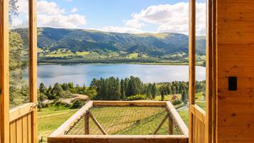 A wooden deck with a view of a lake and surrounding hills.