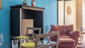 Ein Zimmer mit Glastisch, Stühlen, einer roten Ledersofa und einem Schrank an einer blauen Wand.