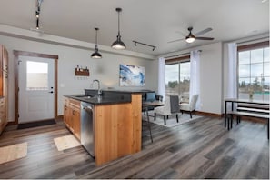 Enjoy meals in a spacious kitchen with a central island, pendant lights, and a large window offering a view of the outdoors.