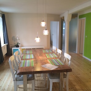 A dining area with a wooden table, white chairs, and hanging pendant lights. - Exclusive loft, quiet and green in Hamburg St Georg, 7 min to the main station (Hamburg)