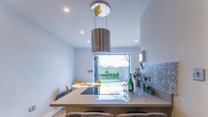 A modern kitchen with a central island, bar stools, and a view of the garden.
