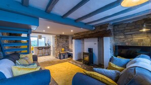 A cozy living room with a stone fireplace, a sofa set, and a rustic stone wall.