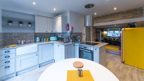 A modern kitchen with white cabinets, a built-in oven, and a yellow refrigerator.