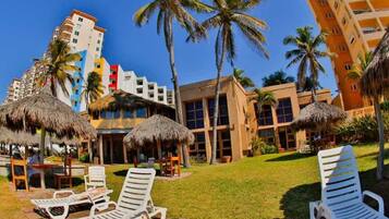 A resort with outdoor seating, palm trees, and modern buildings.
