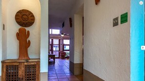 A hallway with a wooden door, a cactus decoration, and a tiled floor leading to a room with a view. - 2BR Garden Villa at Villas el Rancho / unit 1 (mazatlan)