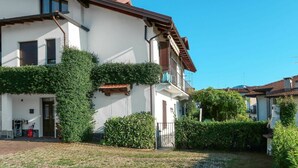Una casa de dos pisos con fachada blanca, un balcón y un jardín.