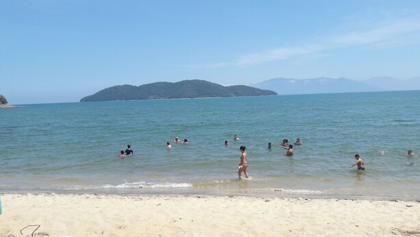 A beach with people swimming and walking along the shore. - House for Season in closed condominium (Caraguatatuba)