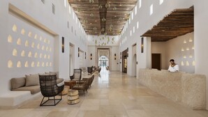A spacious lobby with a reception desk, seating area, and a long corridor leading to a door. - Kedma by Isrotel Design (Ramat Negev)