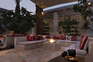 A cozy outdoor seating area with a fire pit, cushioned sofas, and decorative pillows.