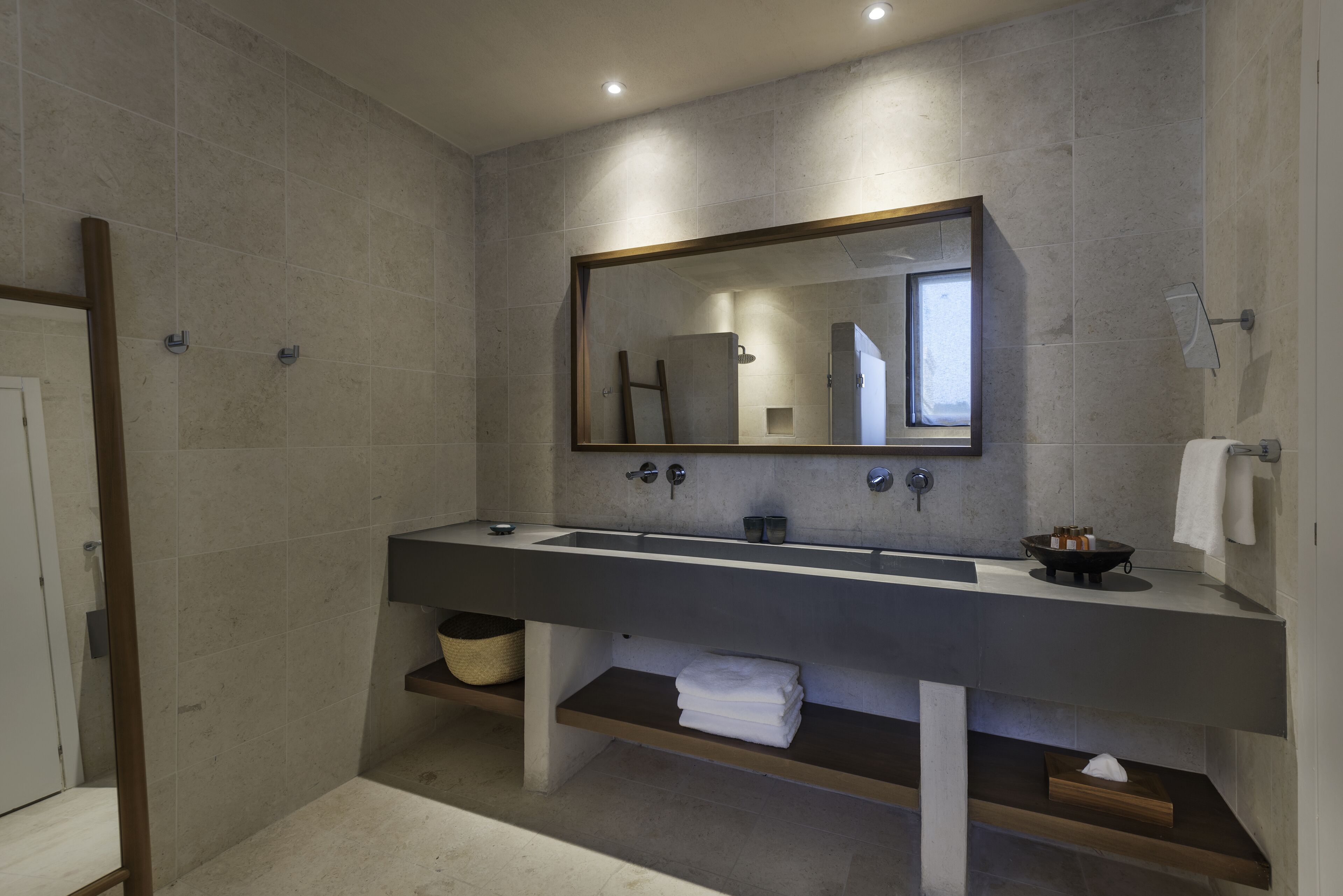 Une salle de bain moderne avec un grand miroir, deux lavabos et un porte-serviettes.