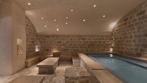 A spa area with a stone wall, a pool, and seating. - Kedma by Isrotel Design (Ramat Negev)