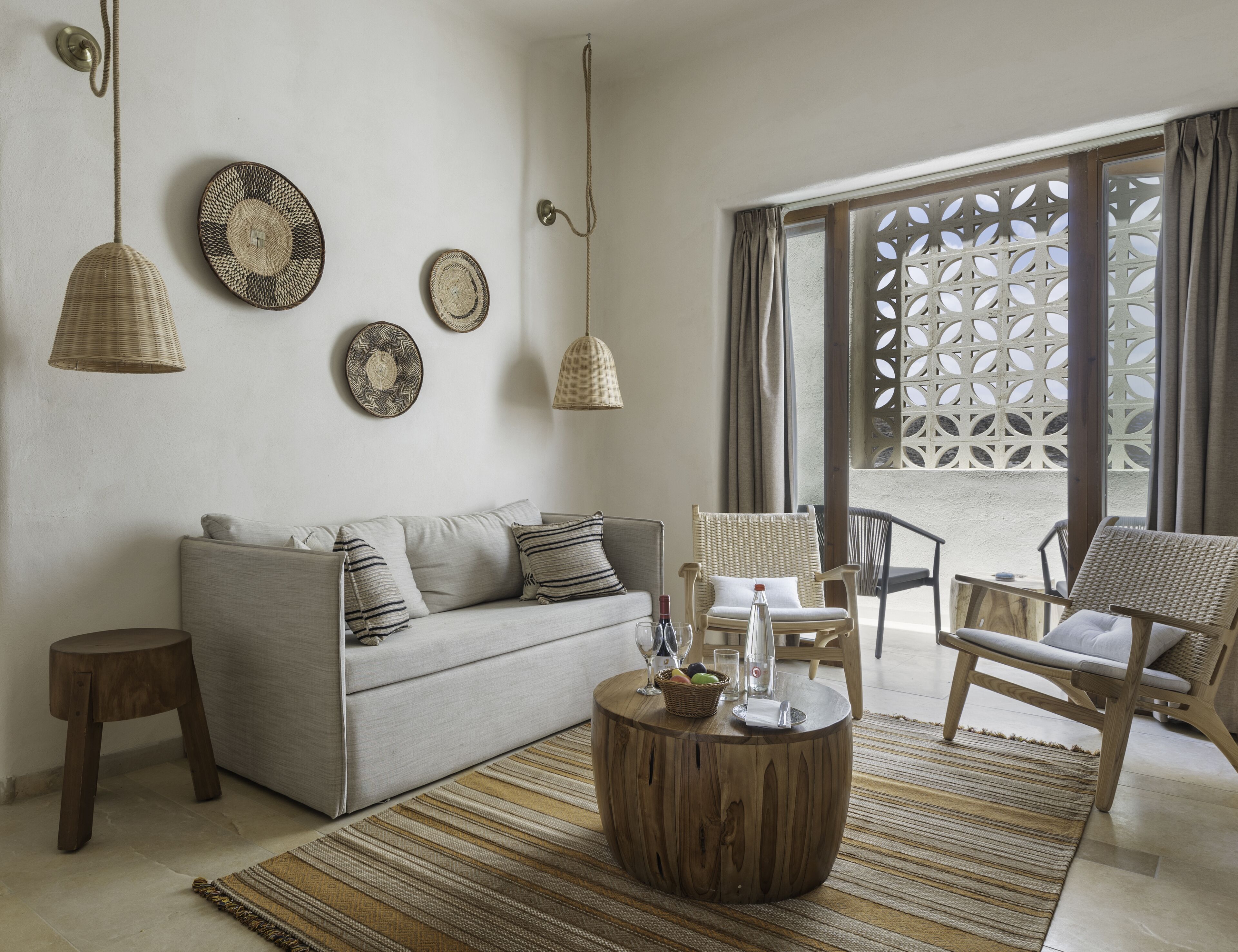 Una sala de estar con sofá, sillas, una mesa de centro y platos decorativos en la pared.