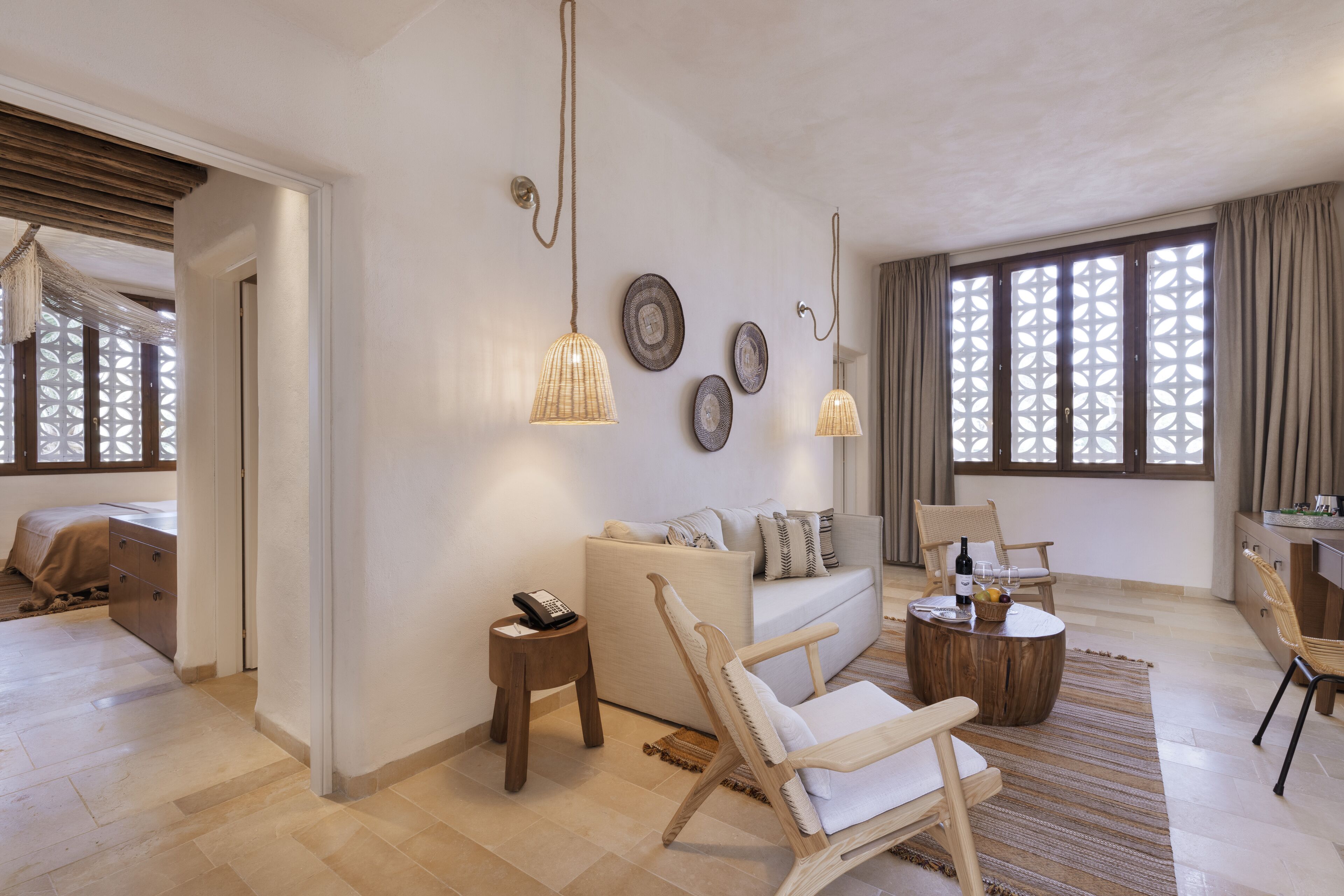 Una sala de estar moderna con un sofá, sillas, una mesa de centro y platos decorativos en la pared.