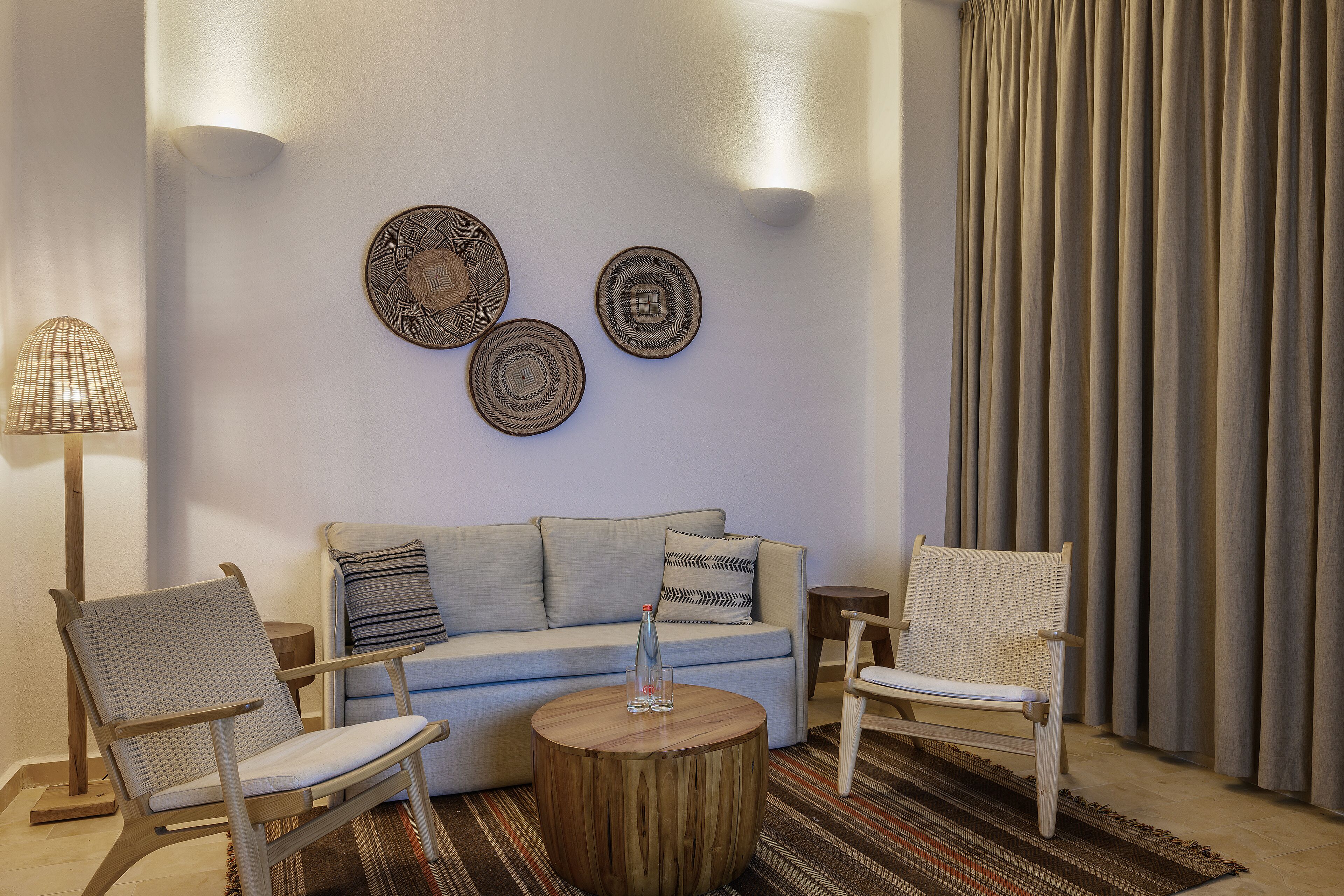 A living room with a sofa, two chairs, a coffee table, and decorative plates on the wall.