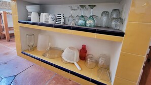 Un piano di lavoro in cucina con scaffali che contengono diversi bicchieri, tra cui tazze, un colapasta e un setaccio.